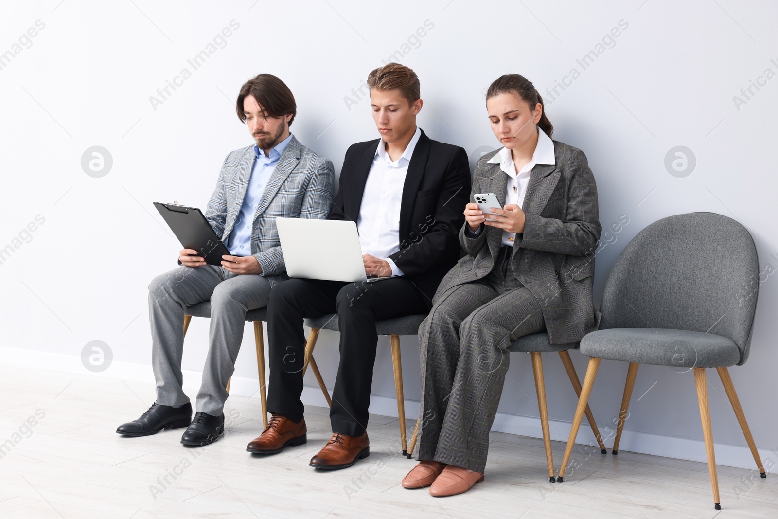 People waiting in queue on chairs indoors Photo of People waiting in queue on chairs indoors