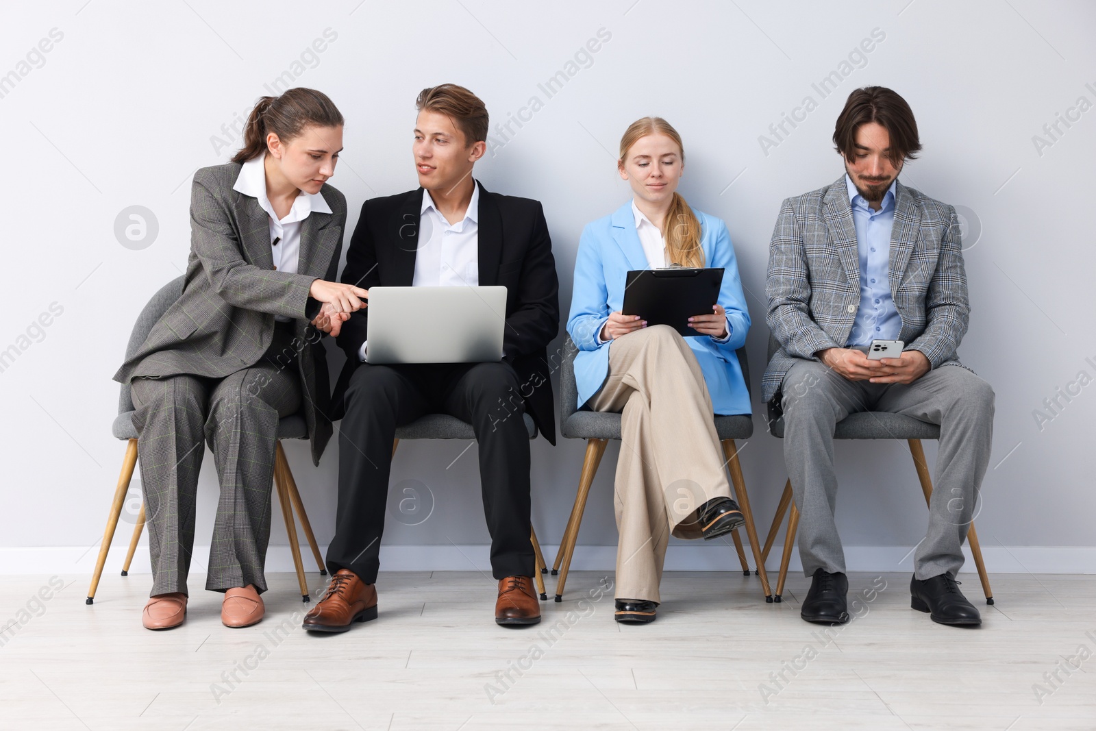 People waiting in queue on chairs indoors Photo of People waiting in queue on chairs indoors