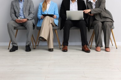 Photo of People waiting in queue on chairs indoors, closeup
