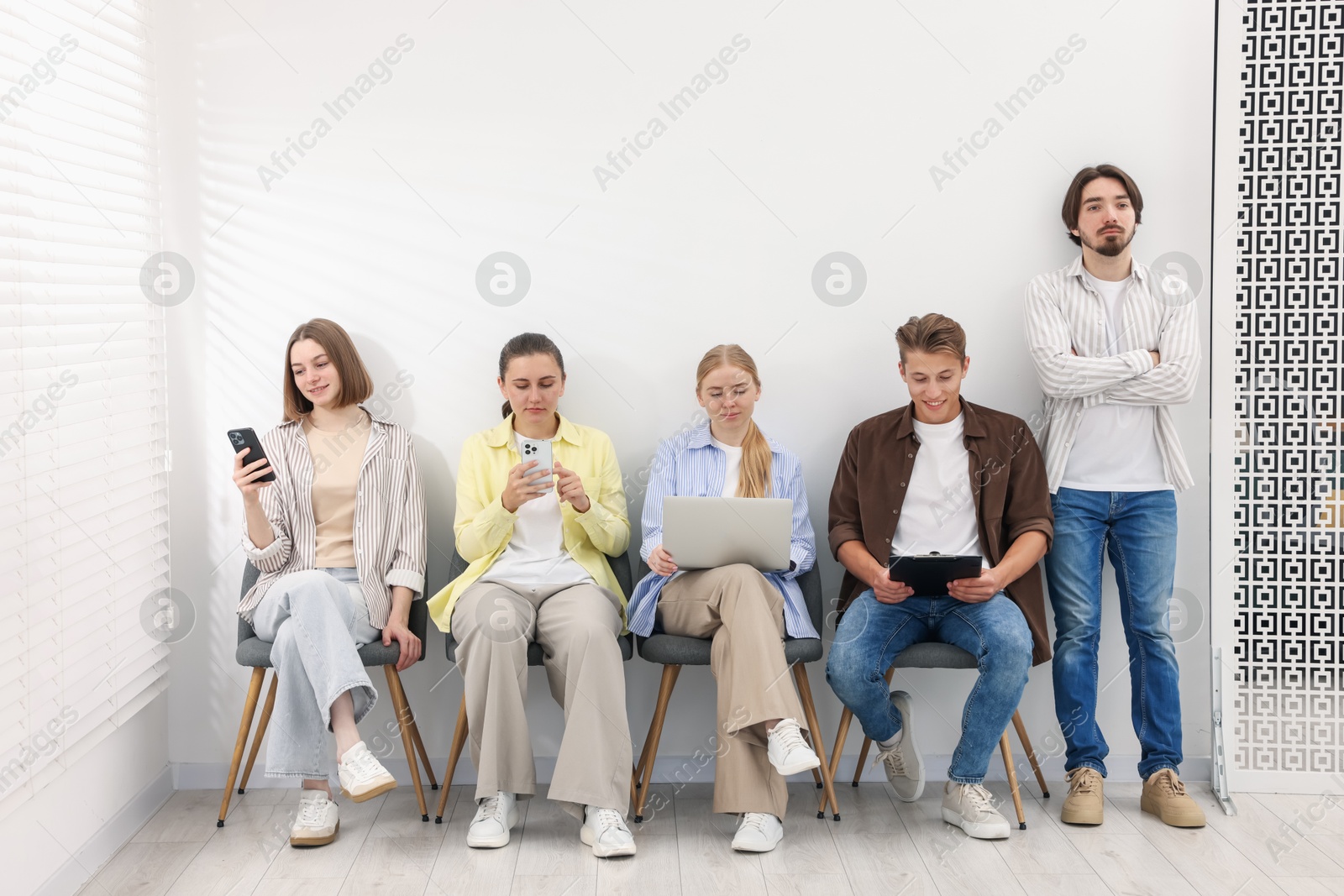 People waiting in queue on chairs indoors Photo of People waiting in queue on chairs indoors