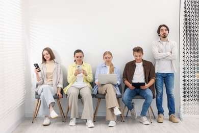 Photo of People waiting in queue on chairs indoors
