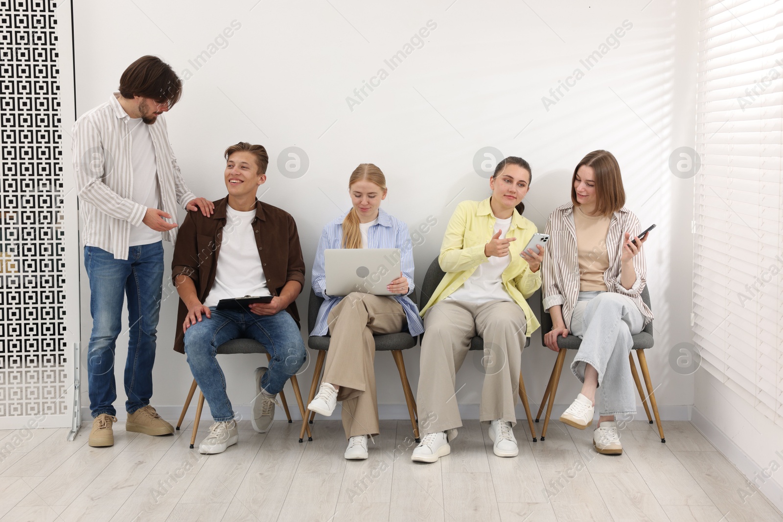People waiting in queue on chairs indoors Photo of People waiting in queue on chairs indoors