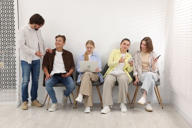 Photo of People waiting in queue on chairs indoors
