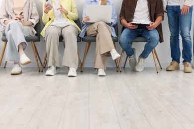 Photo of People waiting in queue on chairs indoors, closeup
