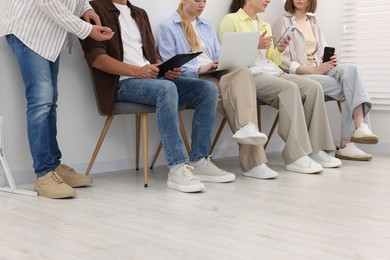 Photo of People waiting in queue on chairs indoors, closeup