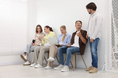 Photo of People waiting in queue on chairs indoors