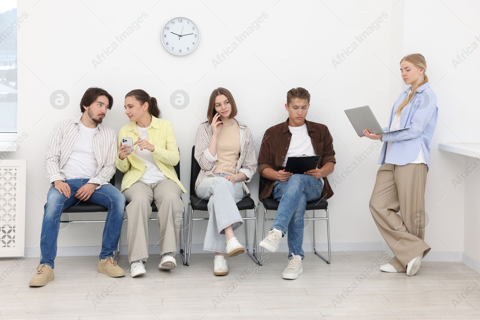 People waiting in queue on chairs indoors Photo of People waiting in queue on chairs indoors