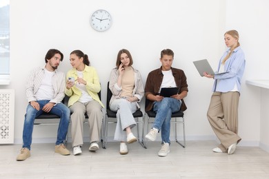 Photo of People waiting in queue on chairs indoors