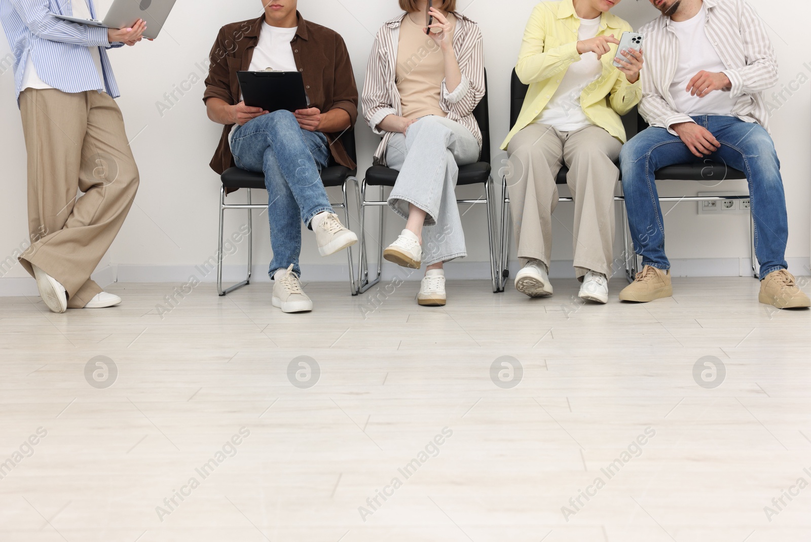 People waiting in queue on chairs indoors Photo of People waiting in queue on chairs indoors