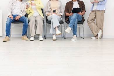 Photo of People waiting in queue on chairs indoors