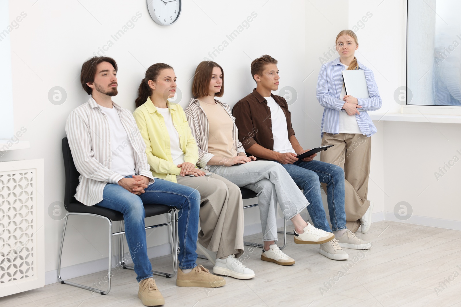 People waiting in queue on chairs indoors Photo of People waiting in queue on chairs indoors
