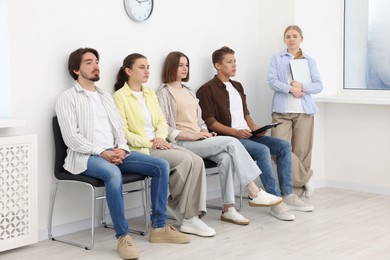 Photo of People waiting in queue on chairs indoors