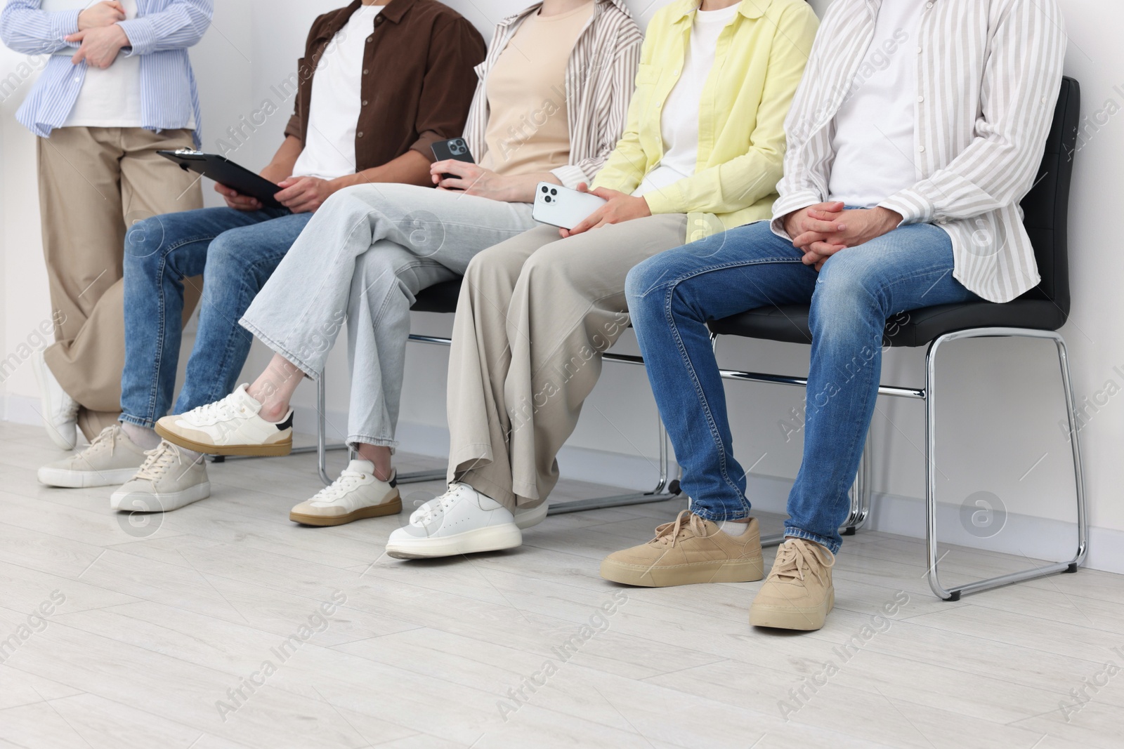 People waiting in queue on chairs indoors, closeup Photo of People waiting in queue on chairs indoors, closeup