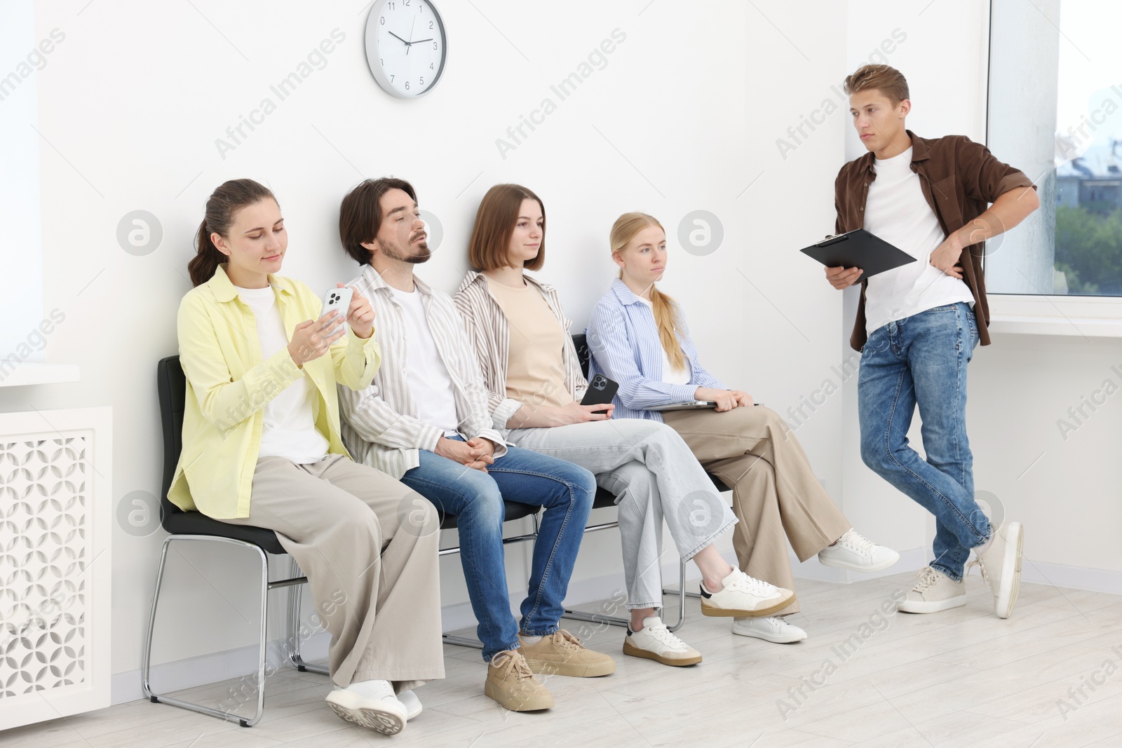 People waiting in queue on chairs indoors Photo of People waiting in queue on chairs indoors