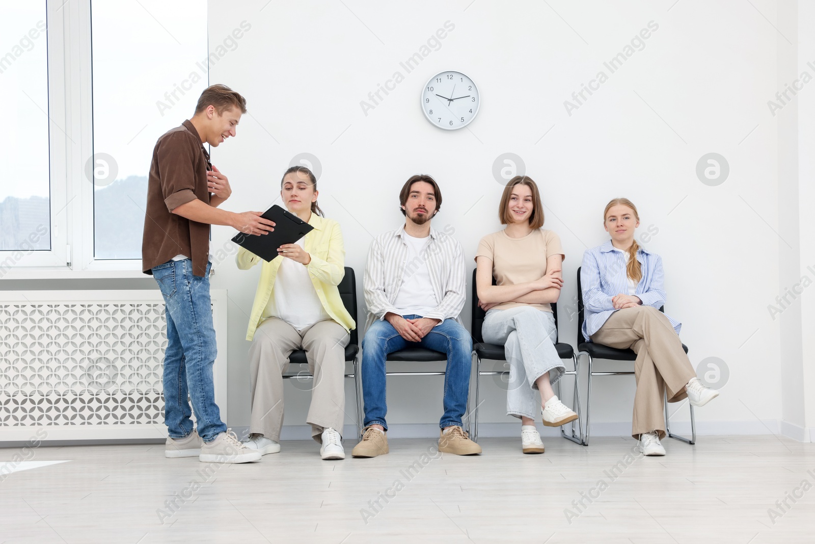 People waiting in queue on chairs indoors Photo of People waiting in queue on chairs indoors