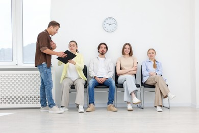 Photo of People waiting in queue on chairs indoors
