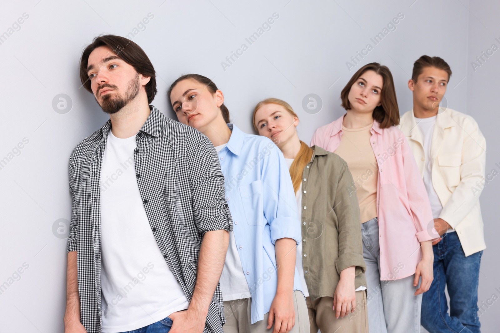 Group of people waiting in queue near light grey wall indoors Photo of Group of people waiting in queue near light grey wall indoors