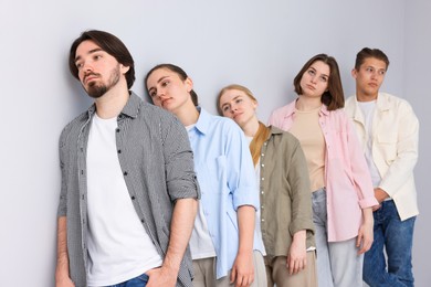 Photo of Group of people waiting in queue near light grey wall indoors