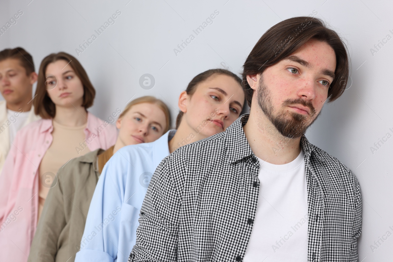 Group of people waiting in queue near light grey wall indoors Photo of Group of people waiting in queue near light grey wall indoors