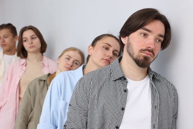 Photo of Group of people waiting in queue near light grey wall indoors