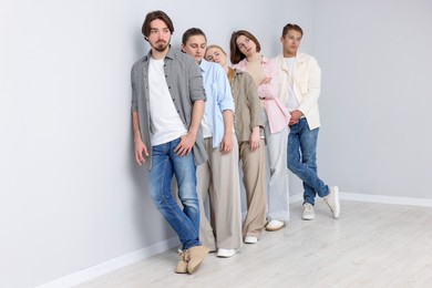 Photo of Group of people waiting in queue near light grey wall indoors