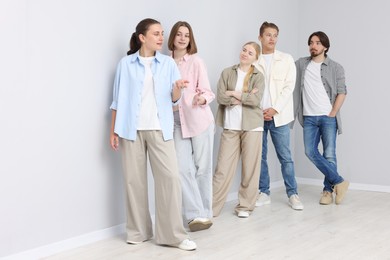 Photo of Group of people waiting in queue near light grey wall indoors