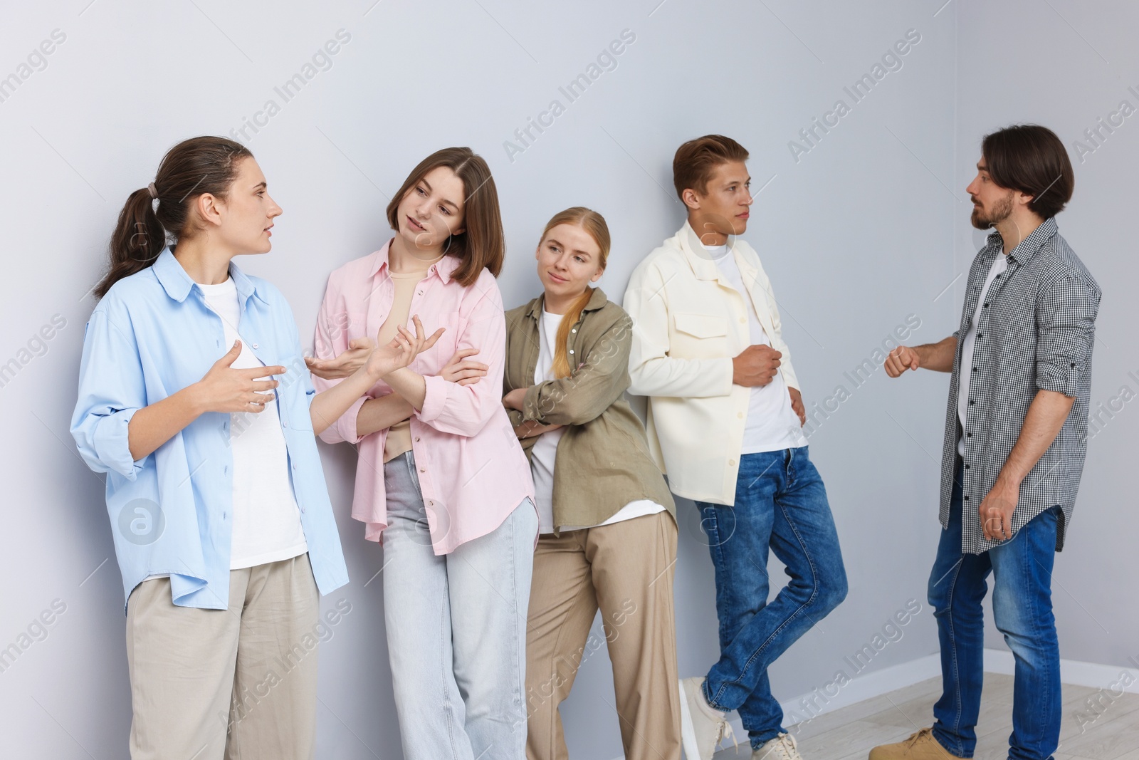 Group of people waiting in queue near light grey wall indoors Photo of Group of people waiting in queue near light grey wall indoors