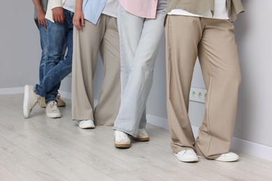Photo of Group of people waiting in queue near light grey wall indoors, closeup