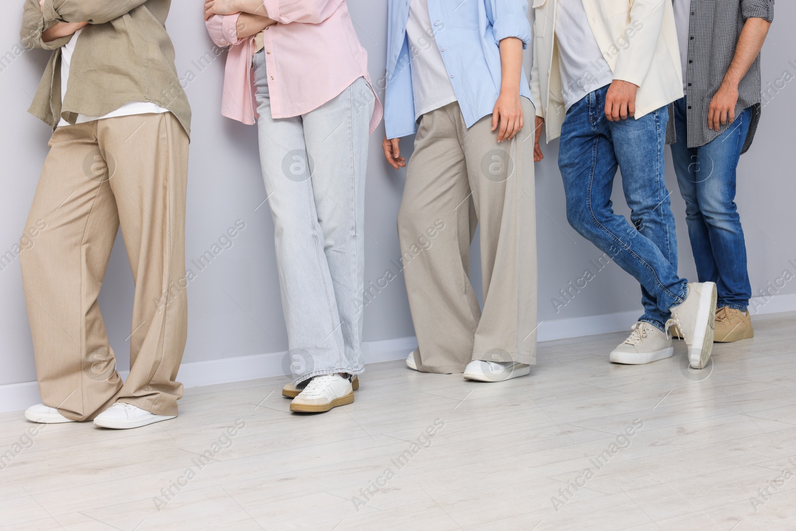 Group of people waiting in queue near light grey wall indoors, closeup Photo of Group of people waiting in queue near light grey wall indoors, closeup