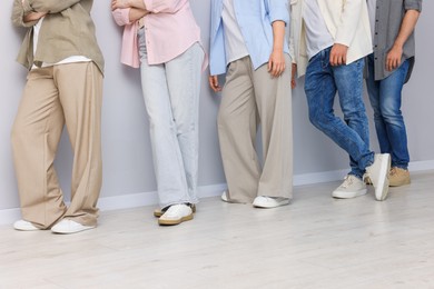 Photo of Group of people waiting in queue near light grey wall indoors, closeup