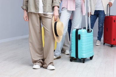 Photo of Group of people with luggages waiting in queue indoors, closeup