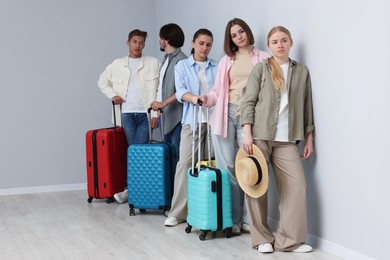 Photo of Group of people with luggages waiting in queue indoors