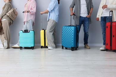 Photo of Group of people with luggages waiting in queue indoors, closeup