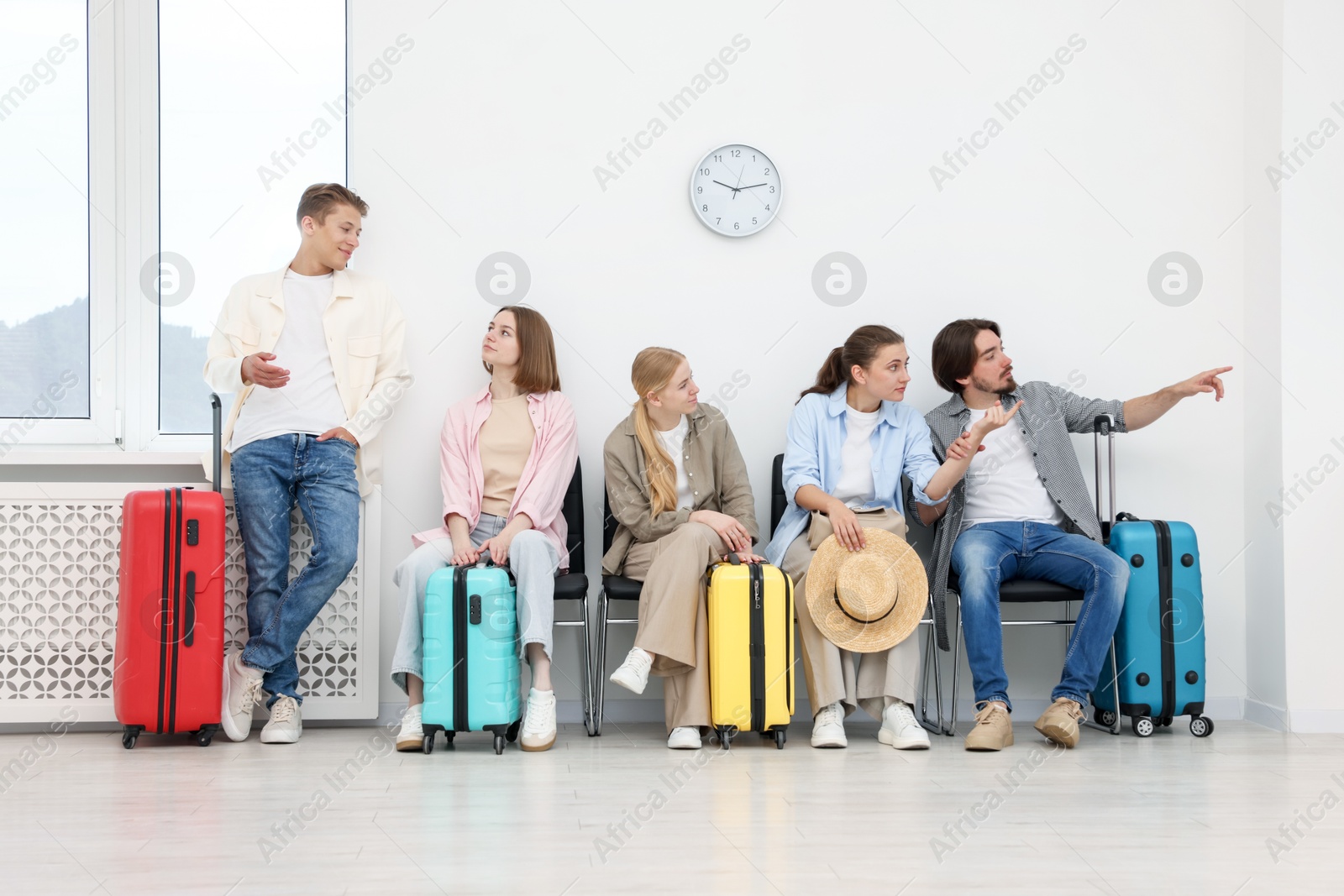 People with luggages waiting in queue on chairs indoors Photo of People with luggages waiting in queue on chairs indoors