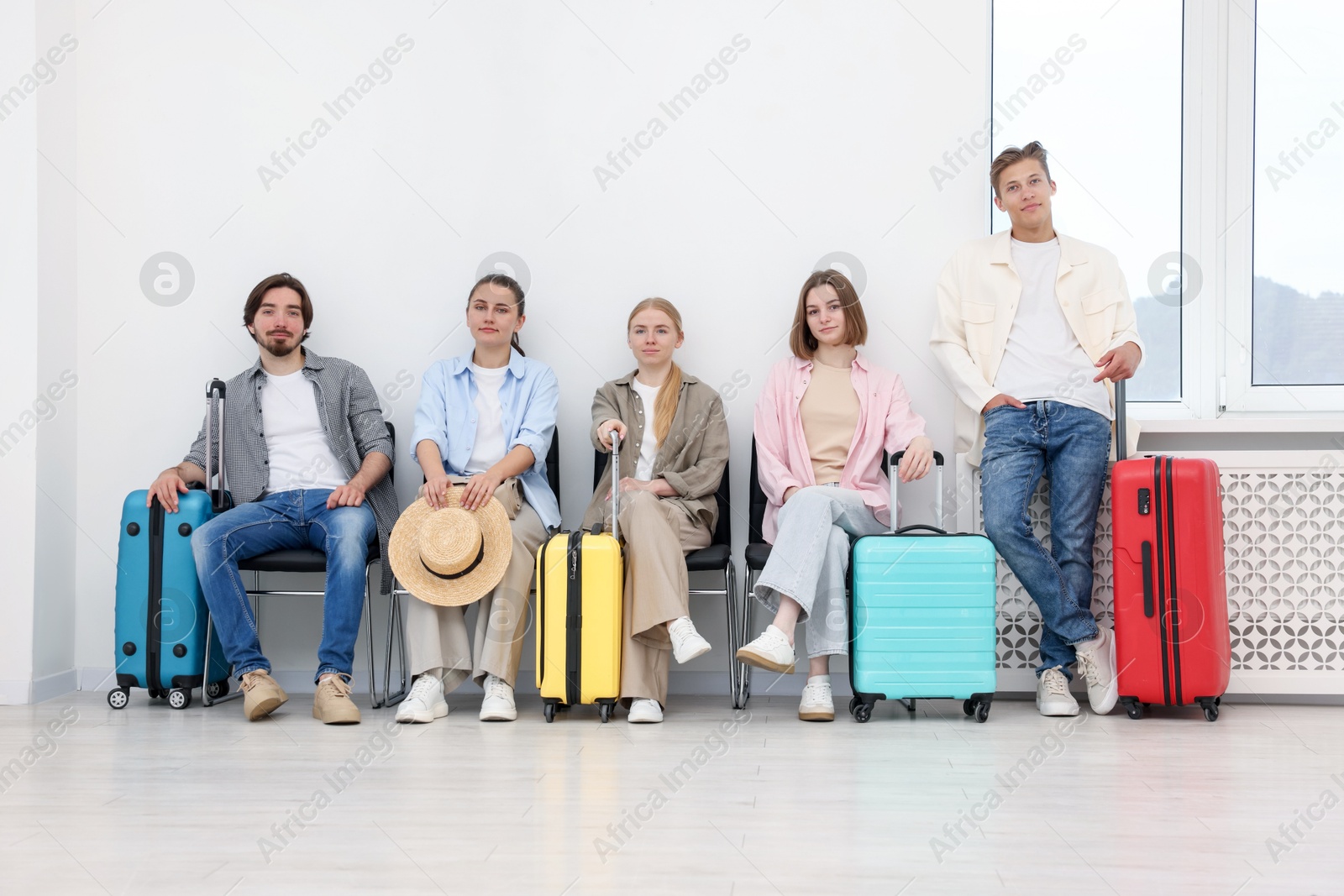People with luggages waiting in queue on chairs indoors Photo of People with luggages waiting in queue on chairs indoors