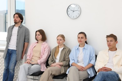 Photo of People waiting in queue on chairs indoors