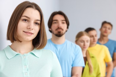 Photo of Group of people waiting in queue indoors, selective focus
