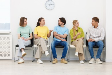 Photo of People waiting in queue on chairs indoors