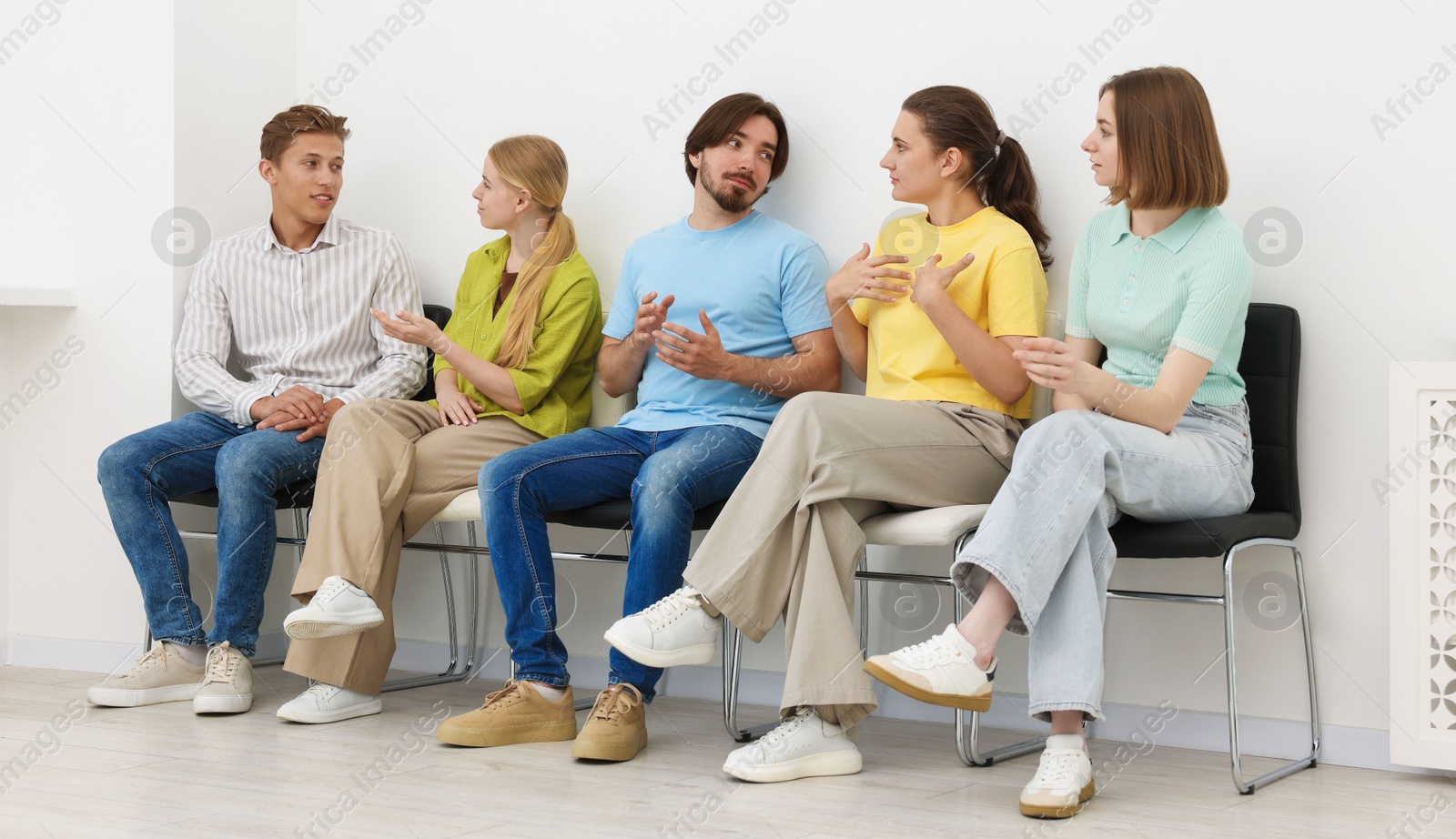 People waiting in queue on chairs indoors Photo of People waiting in queue on chairs indoors