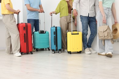 Photo of People with luggages waiting in queue indoors, closeup