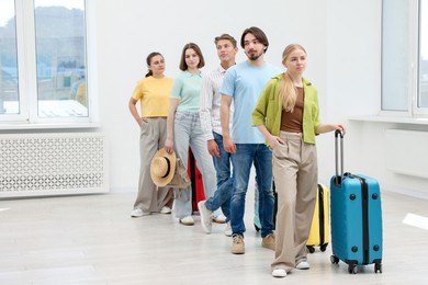 Photo of People with luggages waiting in queue indoors