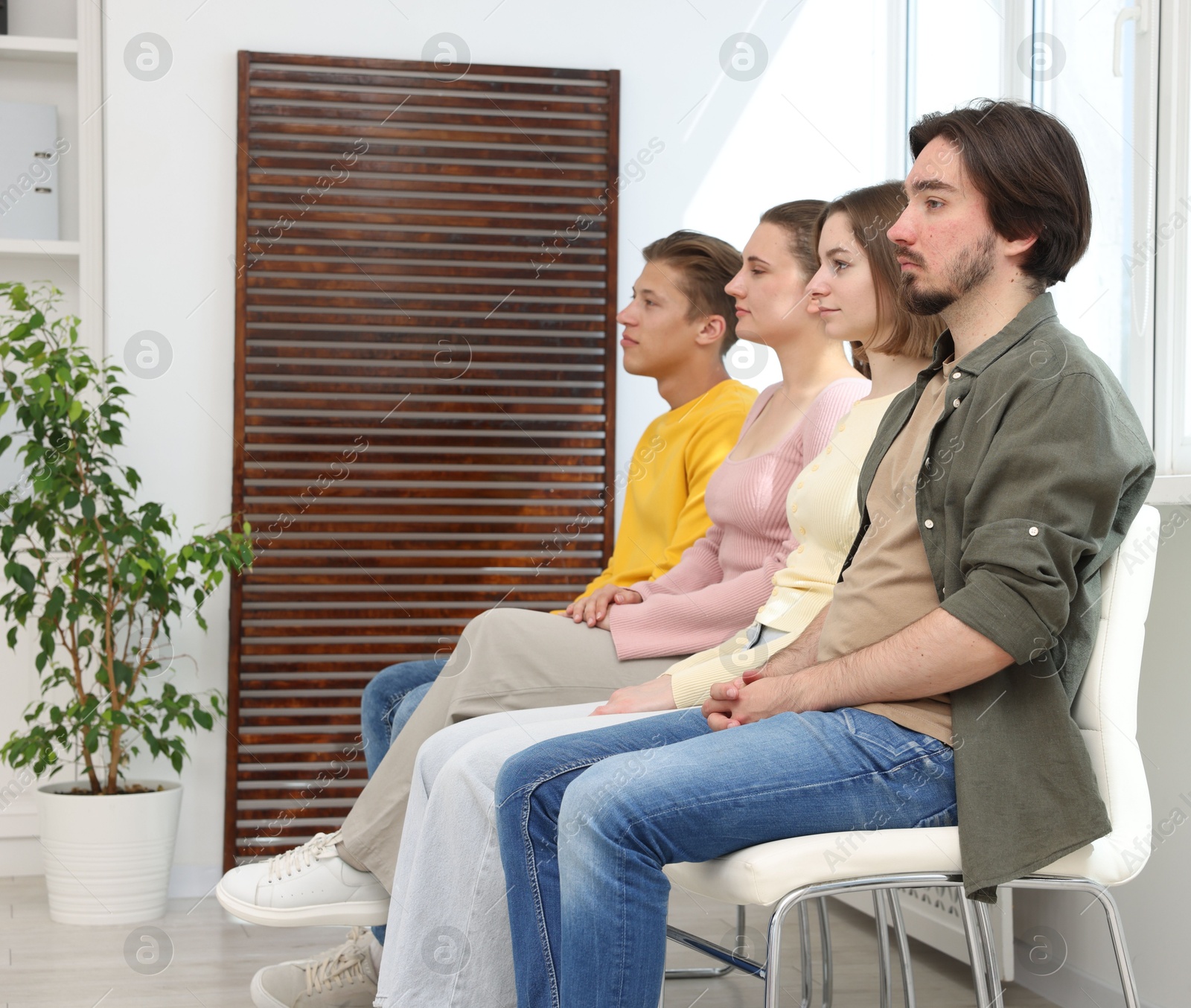 People waiting in queue on chairs indoors Photo of People waiting in queue on chairs indoors