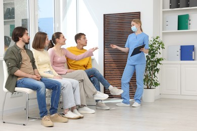Photo of People waiting in queue on chairs at hospital