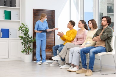 Photo of People waiting in queue on chairs at hospital