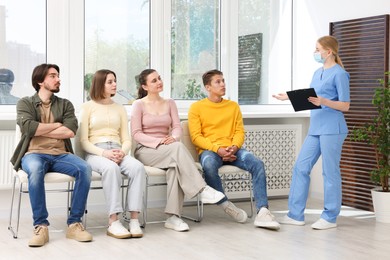 Photo of People waiting in queue on chairs at hospital