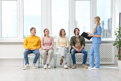 Photo of People waiting in queue on chairs at hospital