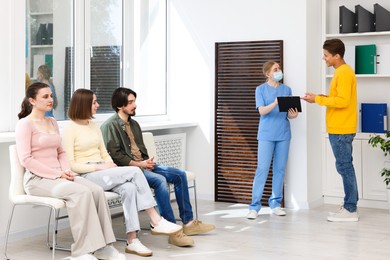 Photo of People waiting in queue on chairs at hospital