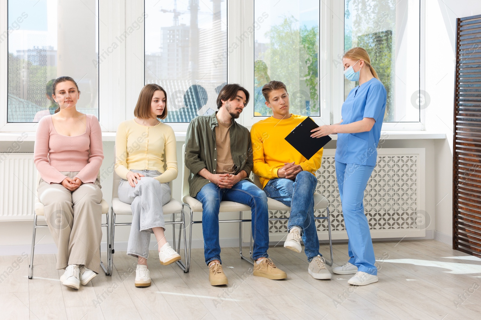 People waiting in queue on chairs at hospital Photo of People waiting in queue on chairs at hospital