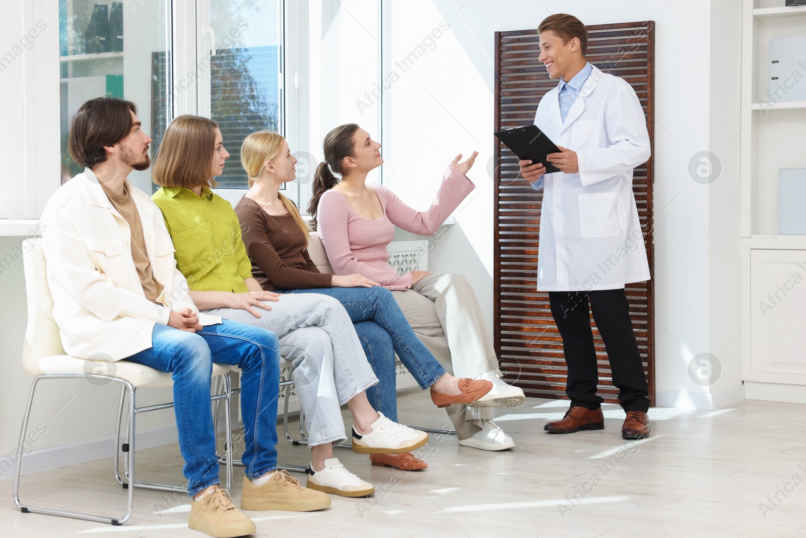 People waiting in queue on chairs at hospital Photo of People waiting in queue on chairs at hospital