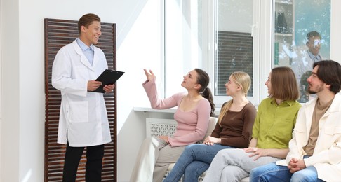 Photo of People waiting in queue on chairs at hospital